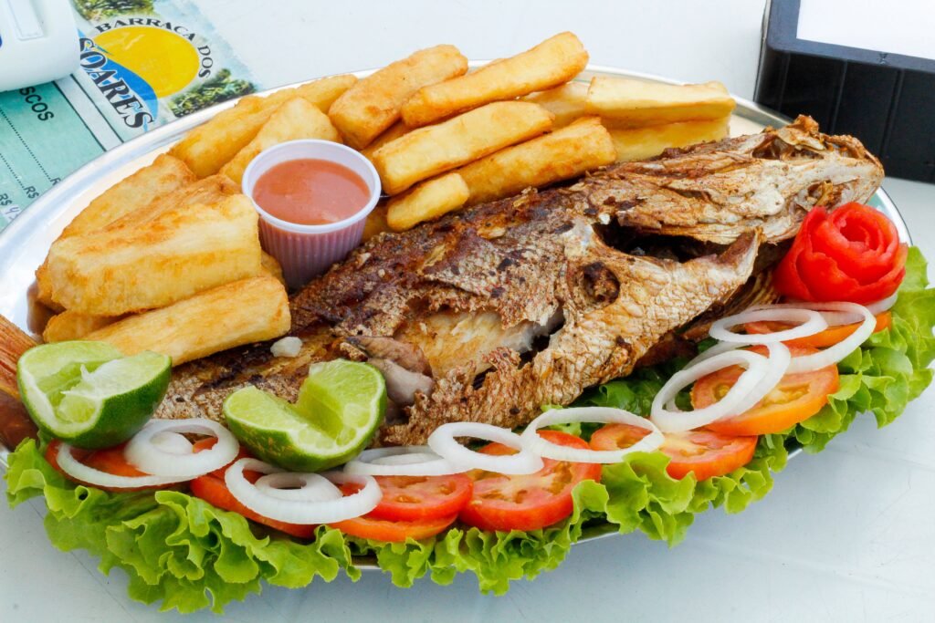 Mouth-watering grilled fish with fries, garnished with fresh vegetables, perfect for a Brazilian meal.